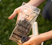Close-up of hands holding a plastic soil test baggie filled with soil
